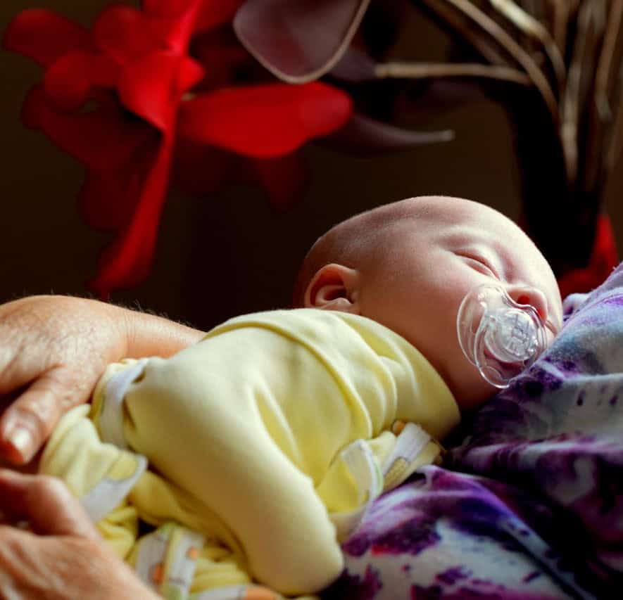 Sleeping infant being held.