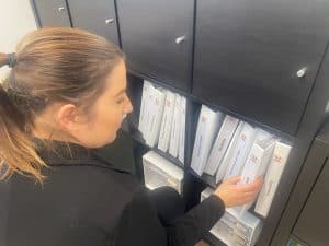 Female individual reaching for a folder - sector research.